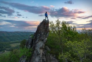 Photo of person standing on large rock outcrop
