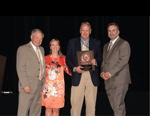 The award winner poses with a plaque next to the SEAFWA president and the award committee chairs