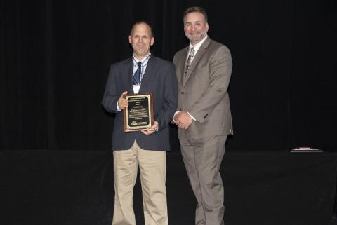 The award winner poses with a plaque next to the SEAFWA president