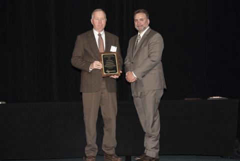 The award winner poses with a plaque next to the SEAFWA president
