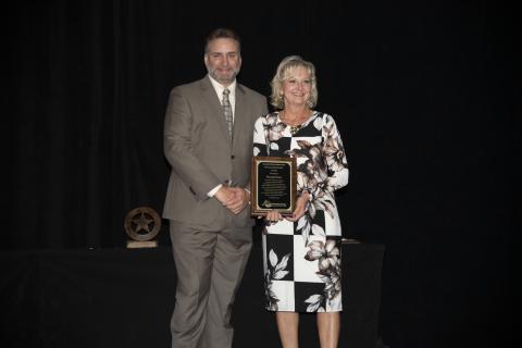 The award winner poses with a plaque next to the SEAFWA president
