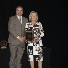 The award winner poses with a plaque next to the SEAFWA president